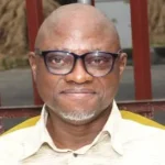 Portrait of Chris Echikwu, a Nigerian commodity market expert and former General Manager for Corporate Communications and Strategy at the Nigeria Commodity Exchange, photographed in a professional setting.